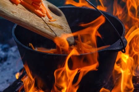 Tourist bowler with food on bonfire, cooking in the hike, outdoor activities. Preparation of pilaf or soup on fire.の写真素材