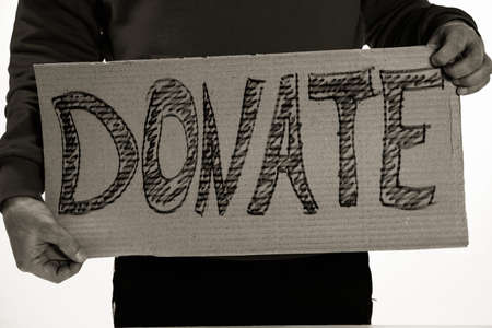 Homeless poor man holding carton board with word DONATE for donationsの写真素材