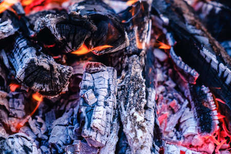 Bright hot coals and burning woods in bbq grill pit. Glowing and flaming charcoal, barbecue, red fire and ash. Weekend recreation background. Close-up, top view.の写真素材