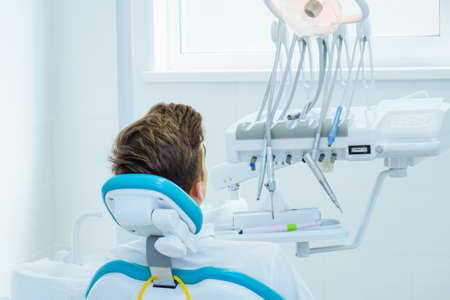 Dental caries prevention. Teenage boy at the dentist's chair during a dental procedure in dentist office.の写真素材