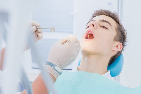 Dental caries prevention.Teenage boy at the dentist's chair during a dental procedure, smile close...