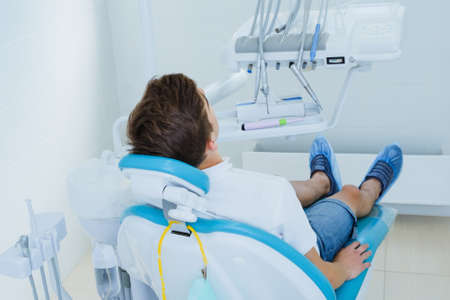 Dental caries prevention. Teenage boy at the dentist's chair during a dental procedure in dentist office.の写真素材