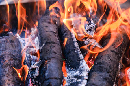 Bright hot coals and burning woods in bbq grill pit. Glowing and flaming charcoal, barbecue, red fire and ash. Weekend recreation background. Close-up, top view.の写真素材