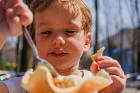 Close-up detail of child eating ice cream. Outdoor at the cafeの写真素材