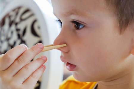 Little funny boy eats Japanese traditional rolls with chopsticks culture, eating sushiの写真素材
