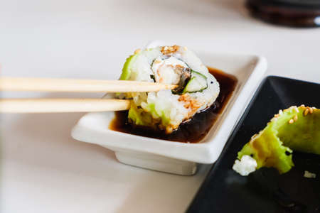 Sushi roll with eel and avocado, chopsticks, tasty soy sauce. Traditional Japanese food.の写真素材