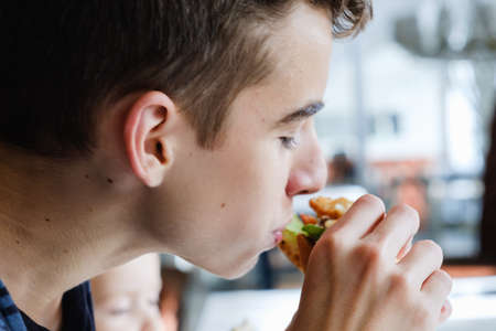 Boy eating Hamburger and french fries in white plate on table, bitten offの写真素材