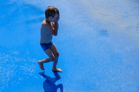 Very Cute little boy. Adorable kid in the fountain. Cheerful pretty child in summer time.の写真素材