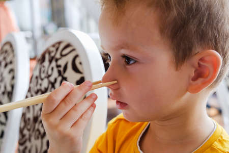 Little funny boy eats Japanese traditional rolls with chopsticks culture, eating sushiの写真素材