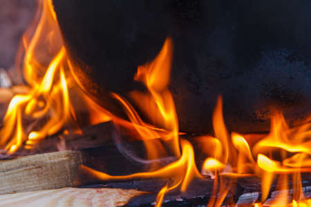 The cauldron with steam on a bonfire. Glowing hot charcoal briquettes close-up background texture coalsの写真素材