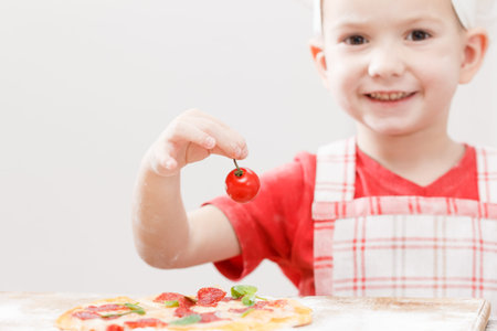 Cook putting tomato over mozzarella on a raw pizza close-upの写真素材