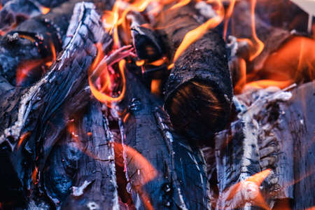 Bright hot coals and burning woods in bbq grill pit. Glowing and flaming charcoal, barbecue, red fire and ash. Weekend recreation background. Close-up, top view.の写真素材