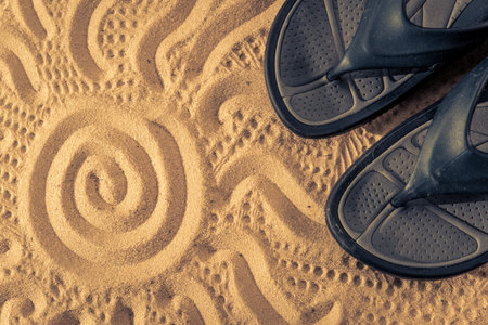 Slippers sands on the beach in the sand stuck to the sneakers with sun art
