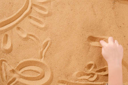 Sand art therapy, child's hands are painted on a table with sandの写真素材