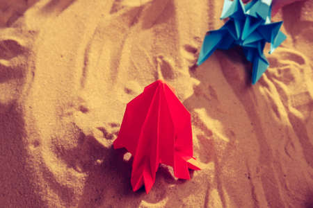 Happy child boy playing with handmade origami paper rocket on beach sand, start up conceptの写真素材