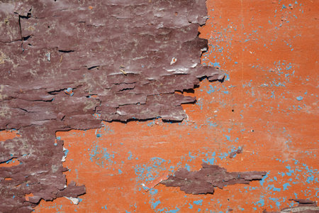 Texture of a peeling orange paint on an old wooden surface.