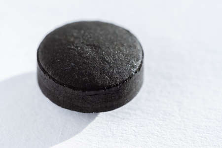 Black Pill tablet medicine lying isolated on white background extreme close-up macro.の写真素材