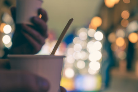 Barista is holding in hands hot cappuccino in white takeaway paper cup. Coffee take away at cafe...