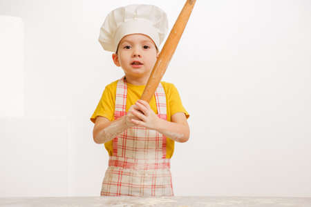 Details of children's hands kneading dough. Cheerful cook child boy in a cap prepares burritos or pizzaの写真素材