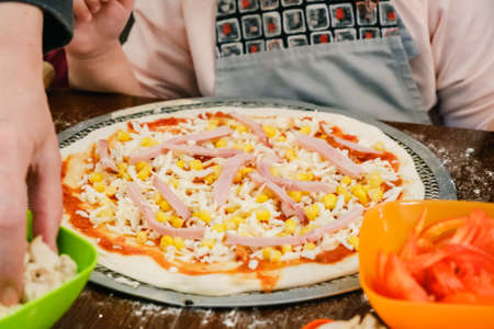 Cooking raw homemade Pizza with fresh ingredient on a wooden background.の写真素材