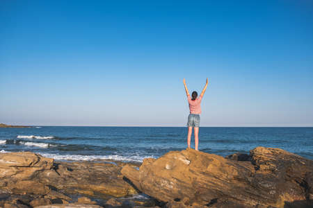 Sea freedom, woman on beach, beautiful girl on rock. see natureの写真素材