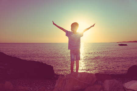 Happy child play on sunset ocean rock sea. foamの写真素材