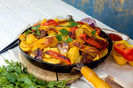 Frying pan with hot baked potatoes on white wooden tableの写真素材