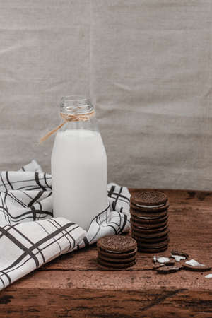 Milk bottle in transparent bottle with chocolate chip cookies on wooden tableの写真素材