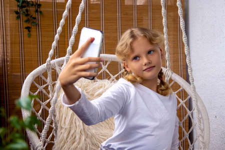 Beautiful teenage girl makes selfie on mobile phone at homeの写真素材