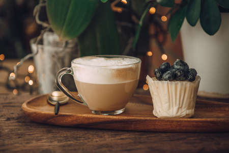 Coffee with milk in a transparent cup and a cake with berries. Breakfast in a cafeの写真素材