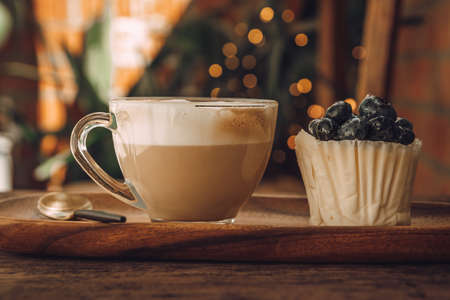 Coffee with milk in a transparent cup and white cupcake with berriesの写真素材