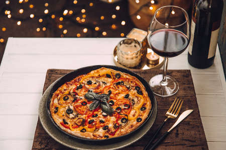 Homemade italian pizza with a glass of red wine on a white wooden table. Dinner on the balconyの写真素材