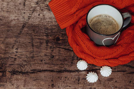 Cup of coffee on a wooden background with a cozy knitted sweater. Free space for textの写真素材