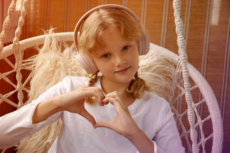 Girl in headphones shows a heart sign with her handsの写真素材