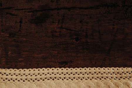 Warm knitted scarf on a dark wooden background. Blank for textの写真素材
