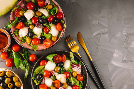Two servings of Italian salad with melon and vegetables on a concrete background. Vegan foodの写真素材