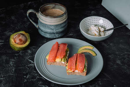 Breakfast on the table - coffee, sandwiches with avocado and salmon. High quality photoの写真素材