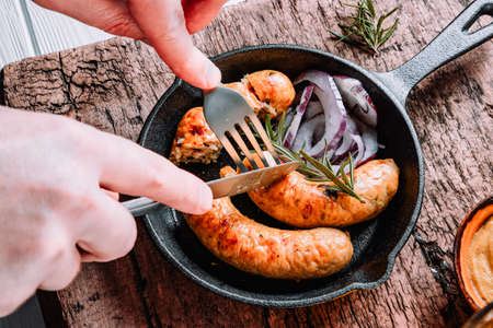 Hands cut bavarian sausages with a knife and a fork. High quality photoの写真素材
