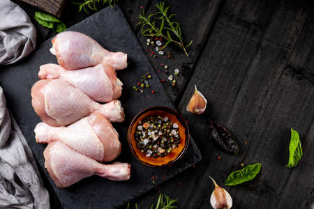Raw chicken legs on a wooden board with spices, top view, copyspace. High quality photoの写真素材