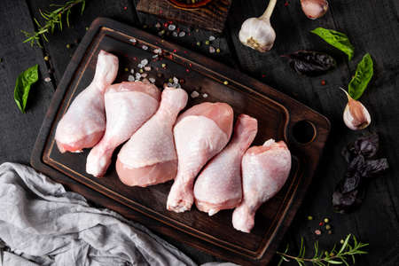 Raw chicken legs on wooden board with spices. High quality photoの写真素材