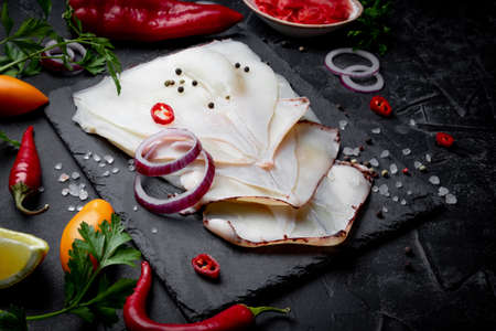 Raw peeled squid and spices for cooking on a slate board and black background. Close-up. High quality photoの写真素材