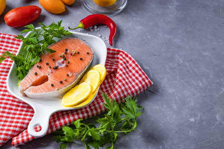 Raw salmon steak on a white plate with seasonings for its preparation, free space for text. High quality photoの写真素材