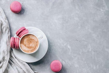 Cup of coffee and small macaroon cakes on gray concrete background, top view, free space for text. High quality photoの写真素材
