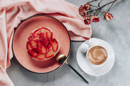 Cup of coffee and cake with strawberries on gray table, top view. High quality photo