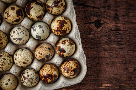 Raw quail eggs on wooden background top view, free space for textの写真素材