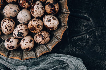 Raw quail eggs in a plate on a black background top view. High quality photoの写真素材