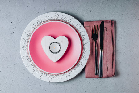 Empty pink plate, cutlery and heart shaped candle. Saint Valentines day table settingの写真素材
