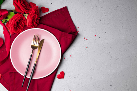 Plate, cutlery and red roses on the gray background, romantic dinner concept. Free space for textの写真素材