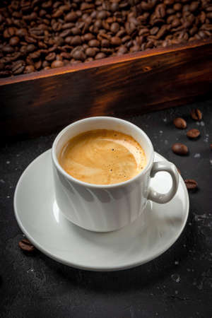 Cup of black coffee and roasted coffee beans in a wooden box vertical photo. High quality photoの写真素材