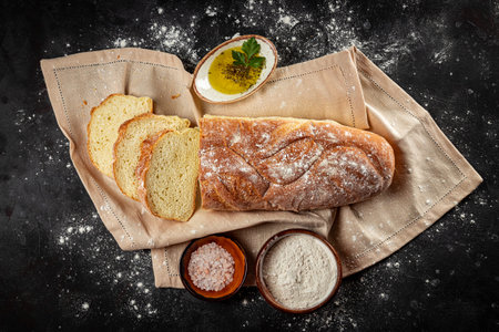 Homemade Italian ciabatta bread sliced into pieces on the dark gray background top view